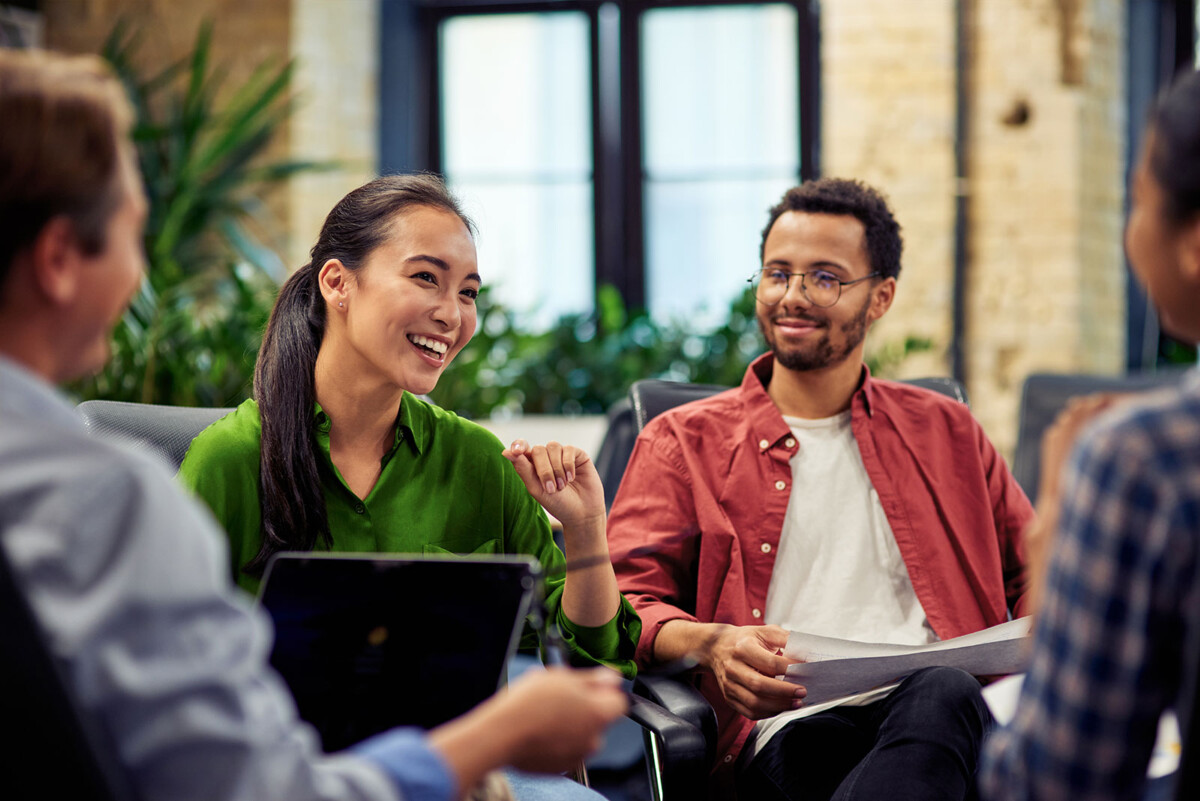Image of people sitting in a circle with laptops working on a project and discussing something