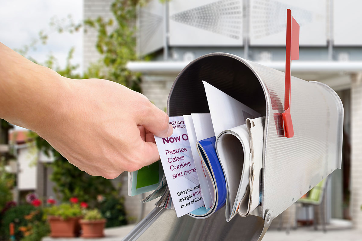 Image of a hand pulling a marketing postcard sent via Every Door Direct Mail from a mailbox.